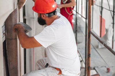 Two cnstruction mason worker on the scaffolding mixing cement and sand with spatula at the construction site