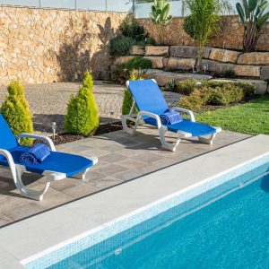 Sunbeds with blue towels, near the pool, for tourists, in the summer. Close-up. High quality photo